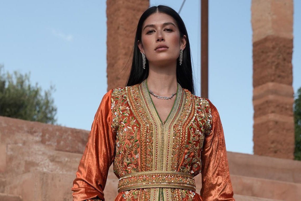 Summer Fall 2026 collection by Bouchra Filali Lahlou, a rust velvet Moroccan kaftan on the steps of a Marrakech riad