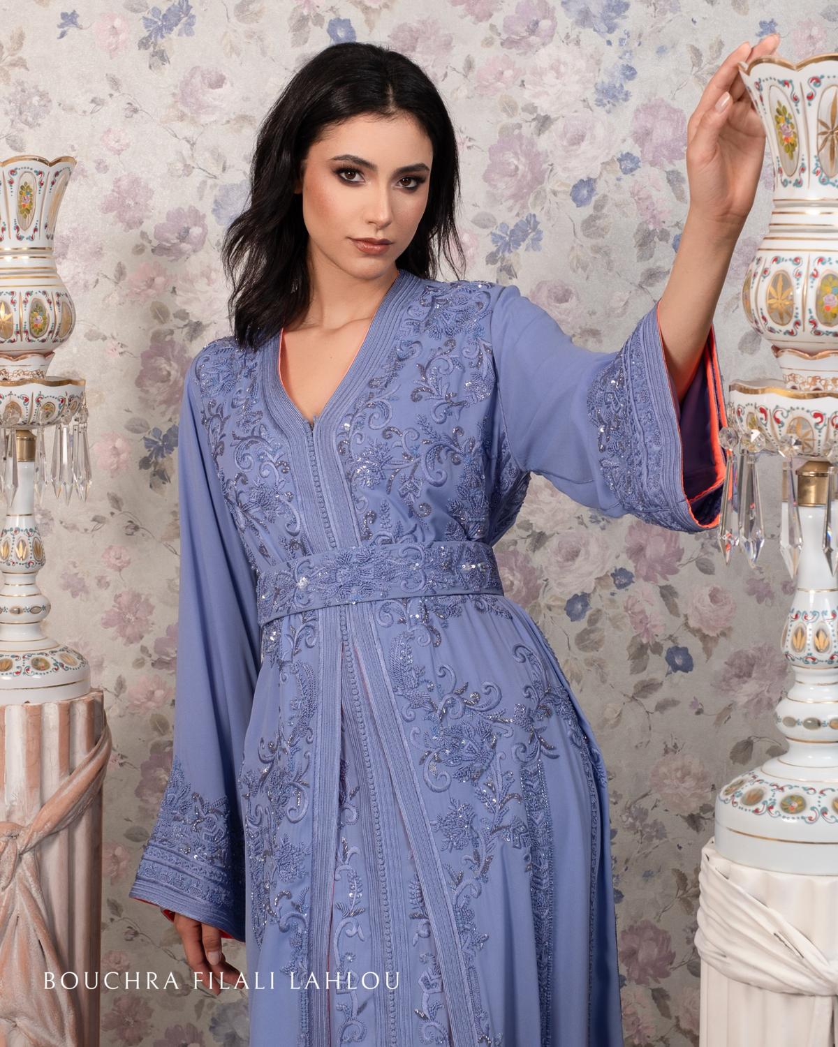 Luxury Moroccan caftan in pastel lilac with hand-sewn detailing and refined finishing, modelled in a floral setting by Bouchra Filali Lahlou